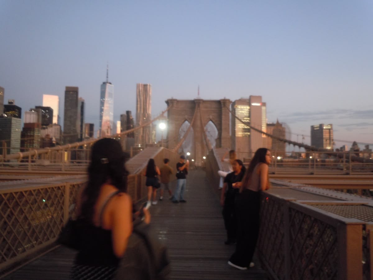 People walking the Brooklyn Bridge at dusk