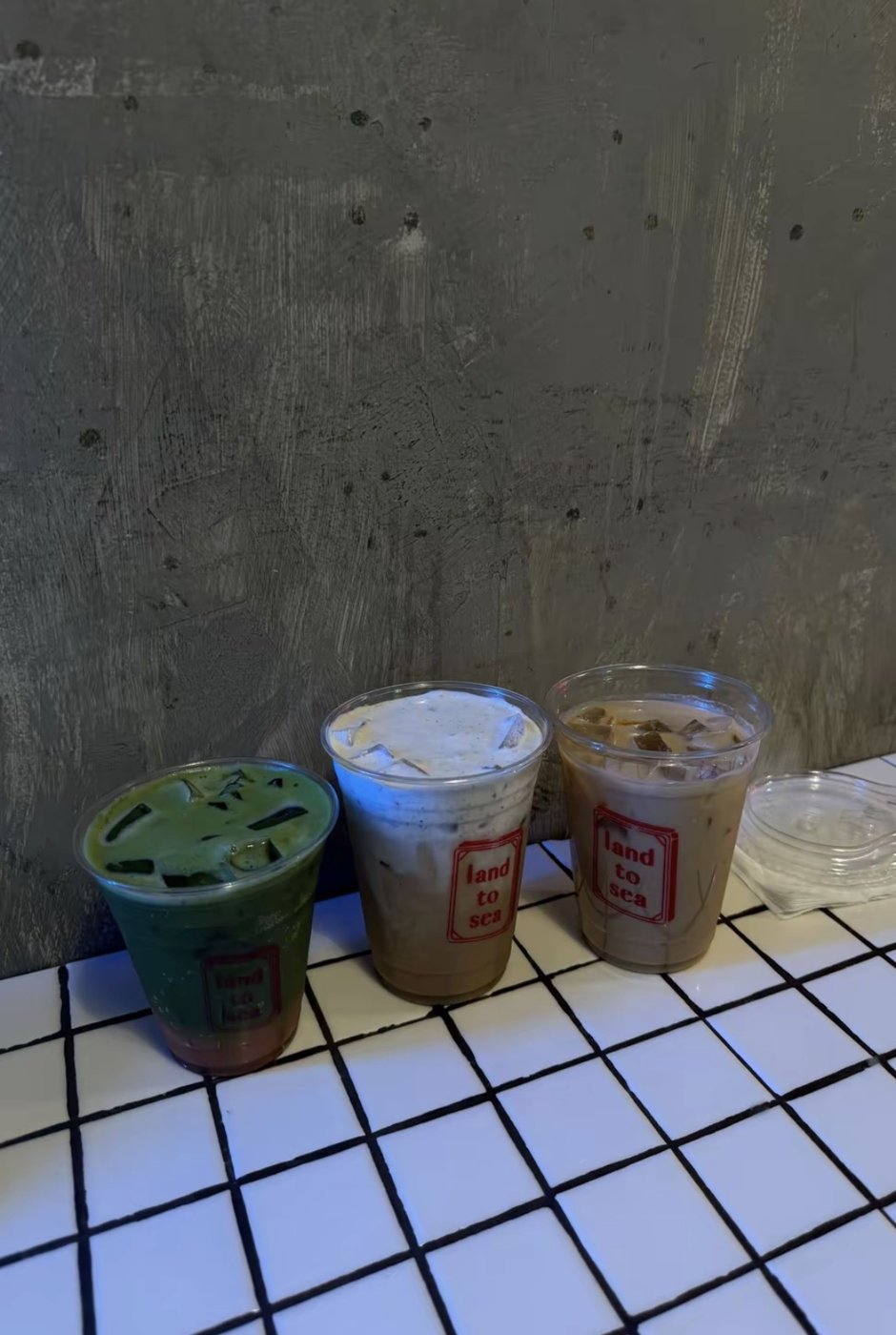 Three iced lattes on a white tiled counter