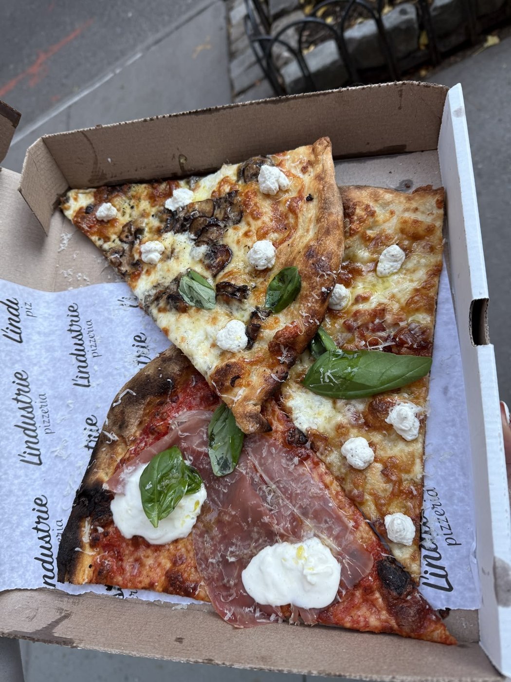 Pizza slices with basil and burrata in an open box