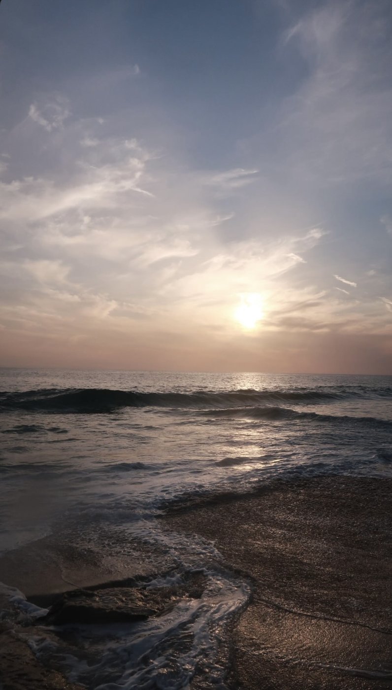 Waves rolling onto the sand under a setting sun