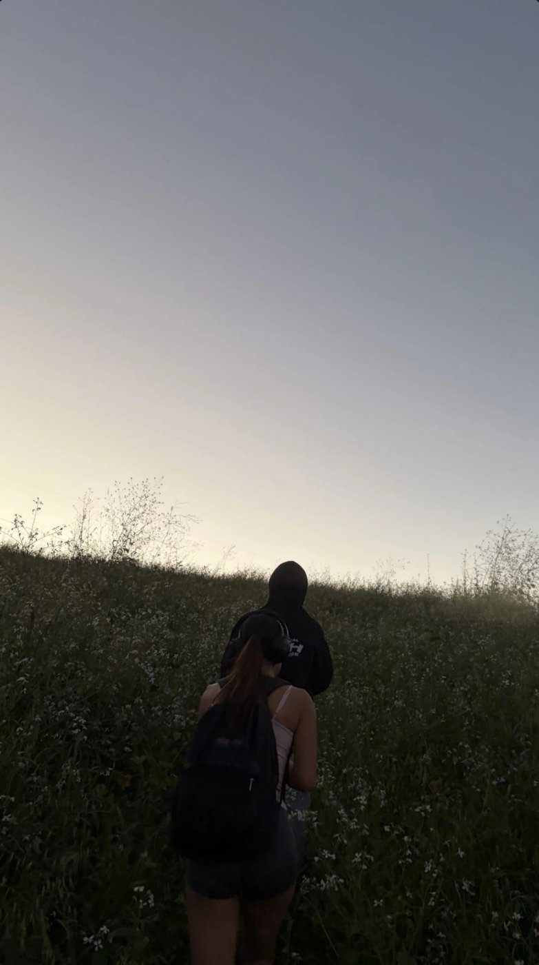 Two friends hiking up a hill of wildflowers at dusk